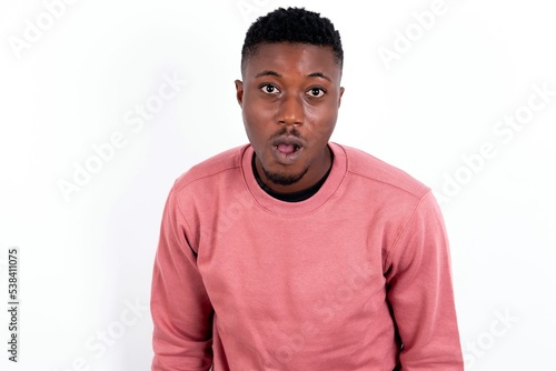 young handsome man wearing pink sweater over white background having stunned and shocked look, with mouth open and jaw dropped exclaiming: Wow, I can't believe this. Surprise and shock