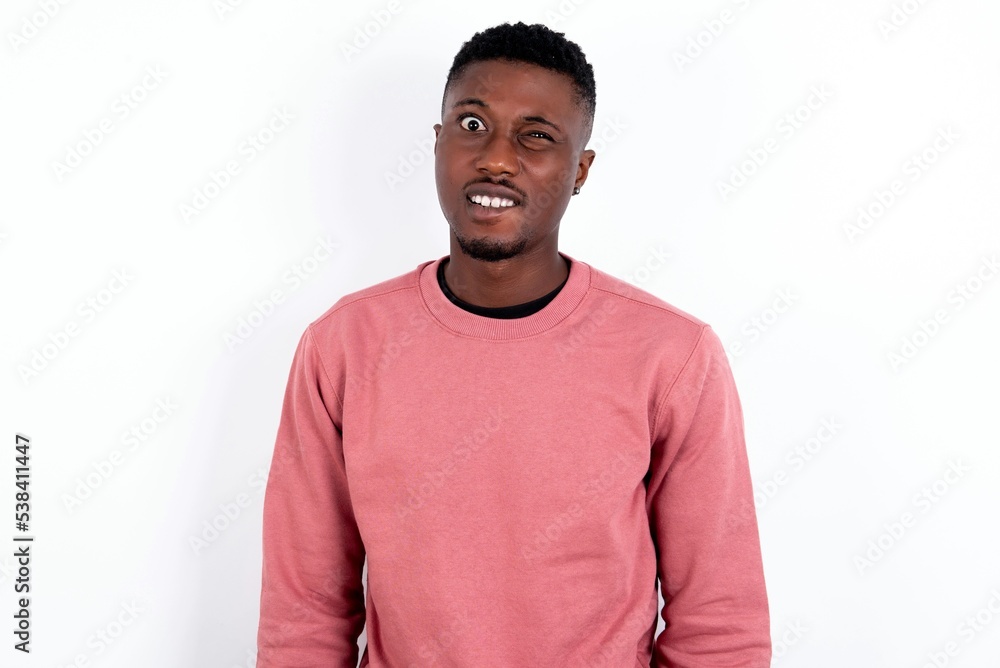 young handsome man wearing pink sweater over white background being nervous and scared biting lips looking camera with impatient expression, pensive. young handsome man wearing pink sweater over white background being nervous and scared biting lips looking camera with impatient expression, pensive.