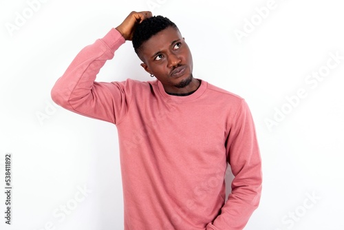 young handsome man wearing pink sweater over white background saying: Oops, what did I do? Holding hand on head with frightened and regret expression.