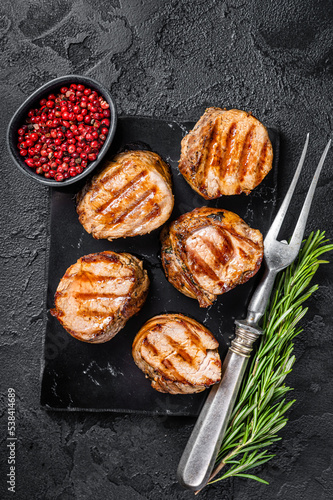 BBQ grilled pork medallions steaks, tenderloin fillet meat. Black background. Top view