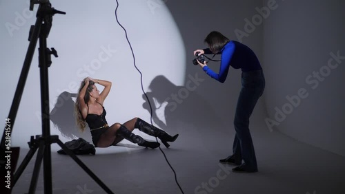 photographing a portrait of a beautiful sexy woman in the studio using a gabo mask and a white cyclorama. woman photographer on the silhouette takes pictures with a digital camera photo