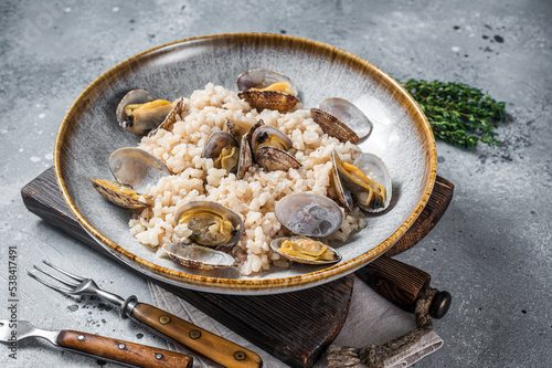 Italian Risotto with clams in a rustic plate with herbs. Gray backgroud. Top view