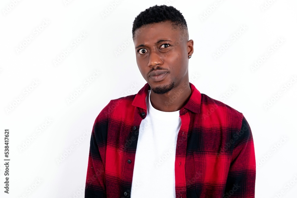 Displeased young handsome man wearing plaid red overshirt over white background frowns face feels unhappy has some problems. Negative emotions and feelings concept Displeased young handsome man wearing plaid red overshirt over white background frowns face feels unhappy has some problems. Negative emotions and feelings concept