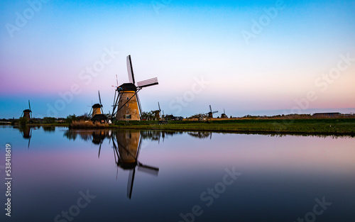 A panoramic photo of the Dutch mills at Kinderdijk with a nice reflection in the water during twilight