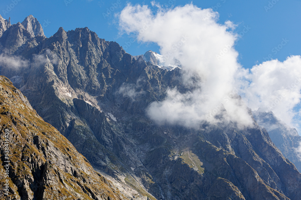 Mountain Range of the Italian Alps on a Sunny Summer Day, close-up view of the Rocks and Blue Sky with Clouds Mountain Range of the Italian Alps on a Sunny Summer Day, close-up view of the Rocks and Blue Sky with Clouds