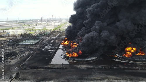 Aerial footage of a large scale Oil refinery with smoke because explosions stacks and petroleum storage tanks. Massive fire explosion or strike in military combat and war.