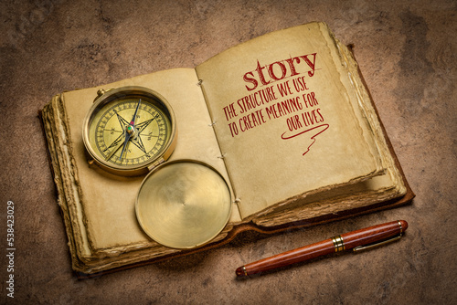 story - the structure we use to create meaning for our lives handwriting in a retro journal with a brass compass, storytelling and interpretation of reality concept
