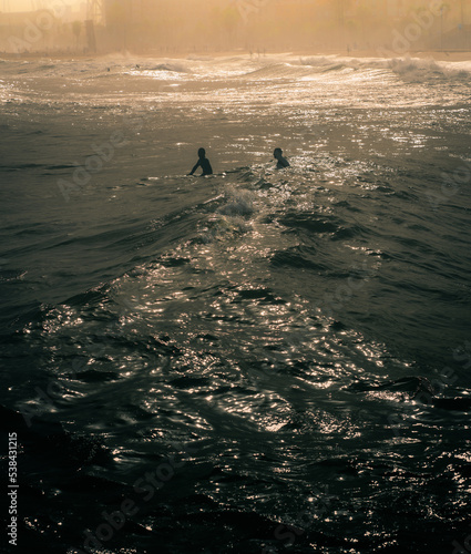 Surfers catching waves near a spanish beach during sunset 