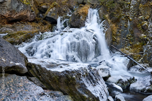 Russia. South of Western Siberia. One of the most beautiful waterfalls of the Altai Mountains on the Karasu River near the village of Chibit on the Chui tract, chained with ice of autumn frosts.