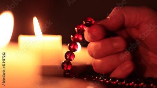 Hand holding rosary against the background of candles photo