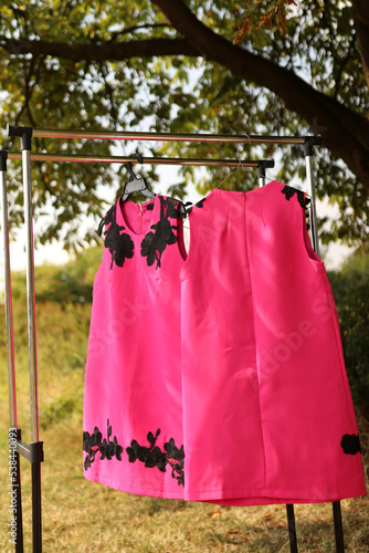 Pink dresses with black elements hang on hangers. © Vasyl