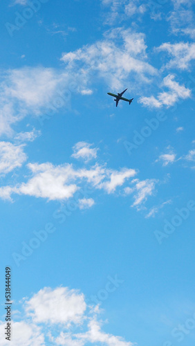 The passenger plane is flying far away in the blue sky and white clouds. Airplane in the air. International passenger air transportation. Vertical stories