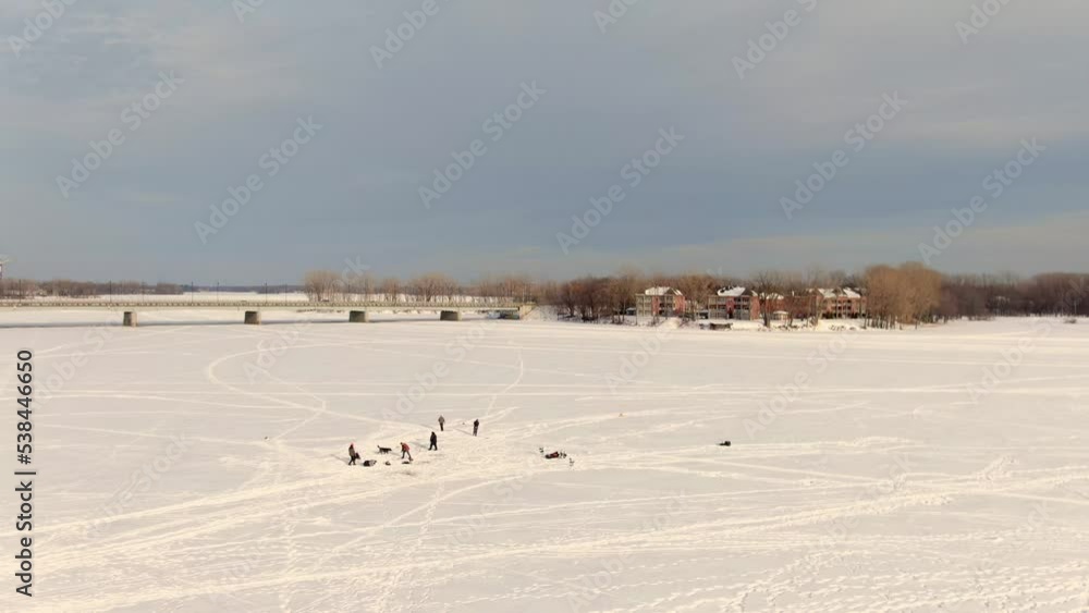 Drone crane view showing the frozen river between St-Eustache and Laval-Ouest and the bridge linking the two sides, with people ice fishing Drone crane view showing the frozen river between St-Eustache and Laval-Ouest and the bridge linking the two sides, with people ice fishing