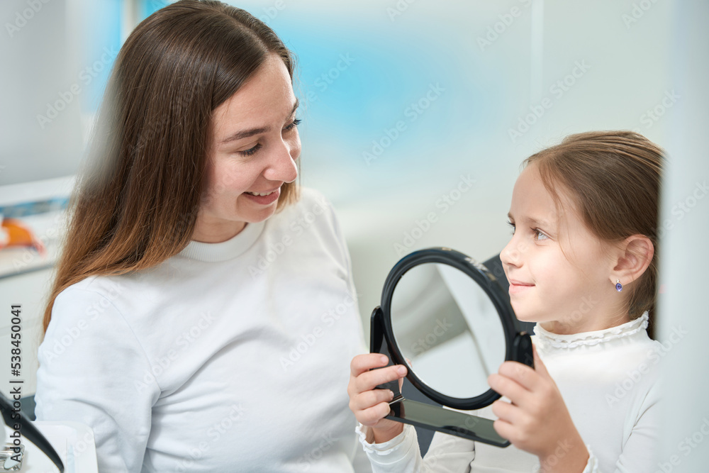 Young patient smiling at her joyous pedodontist after dental treatment Young patient smiling at her joyous pedodontist after dental treatment