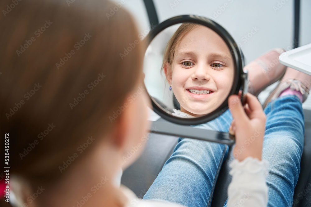 Focused Pre Teen Girl Examining Her Anterior Teeth After Treatment