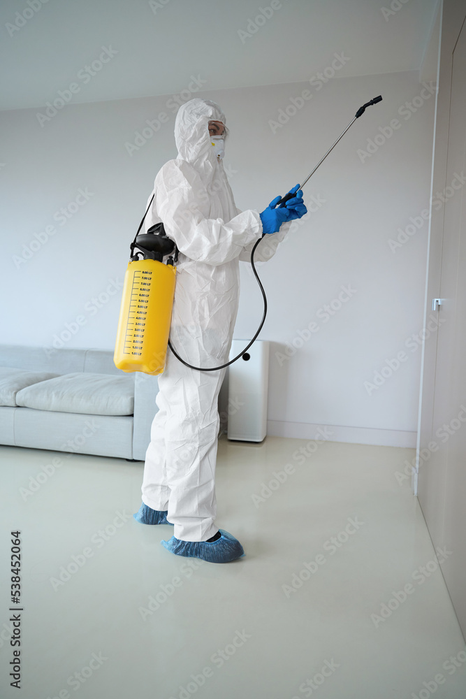 Worker in protective clothes and glasses with sprayer