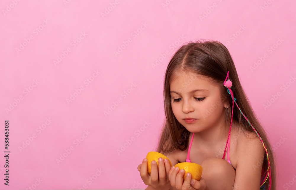 Caucasian beautiful little girl with fresh yellow lemons on a pink background. Little girl with lemon. Funny child isolated on pink. Caucasian beautiful little girl with fresh yellow lemons on a pink background. Little girl with lemon. Funny child isolated on pink.