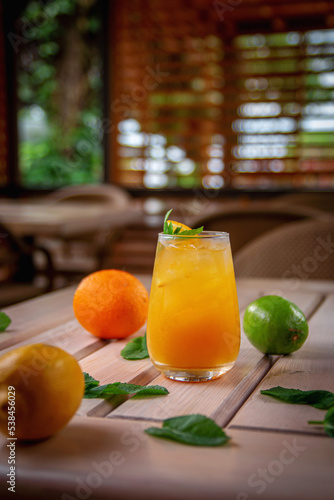 Alcoholic refreshing cocktail with orange, passion fruit and ice cubes, on the summer terrace of the restaurant