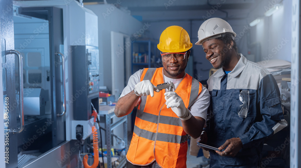 Team work African engineer and afro professional man worker set up and control CNC machinery on industry factory Team work African engineer and afro professional man worker set up and control CNC machinery on industry factory