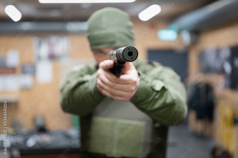 A man is aiming a pistol with a silencer, front view, soft focus photo, the main focus is on the silencer. A man is aiming a pistol with a silencer, front view, soft focus photo, the main focus is on the silencer.