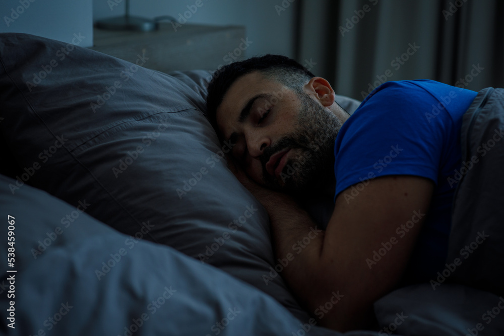 Oriental arabic guy in blue pajamas resting in bed at night Oriental arabic guy in blue pajamas resting in bed at night