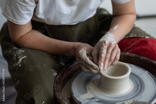 Woman doing pottery on the potter wheel on the workshop