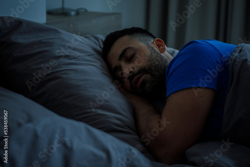 Oriental arabic guy in blue pajamas resting in bed at night
