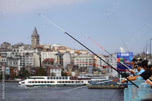 On the Galata Bridge, fishermen are seen with their fishing rods in front of the Istanbul view. Selective Focus. 