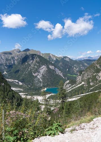 High rocks. Alps in Italy. South Tyrol. Dolomites. Green landscape with stones and trees. Paths in the mountains. Travel. Tourist places. Beautiful nature. Blue clouds