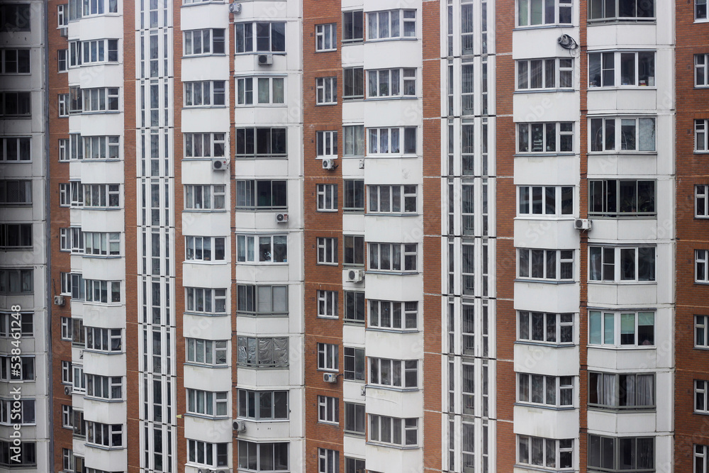 Wall of apartment building with windows and balconies, horizontal photo. Exterior, image for background design, wallpaper. Facade of modern housing construction