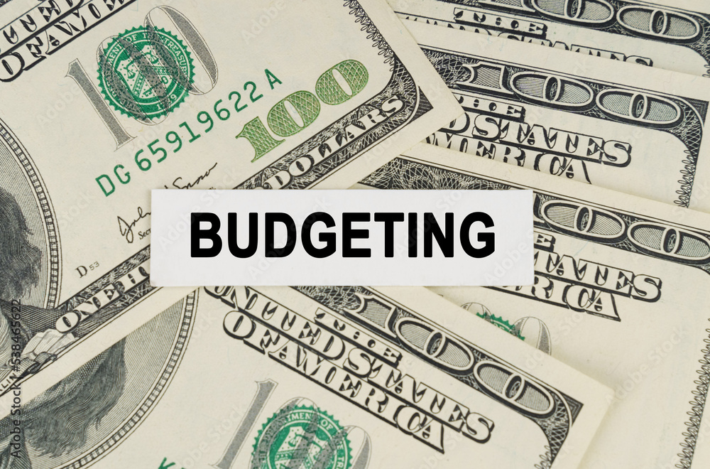 On the dollars lies a paper plate with the inscription - BUDGETING On the dollars lies a paper plate with the inscription - BUDGETING
