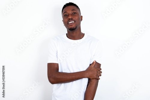 young handsome man wearing white T-shirt over white background laughing.