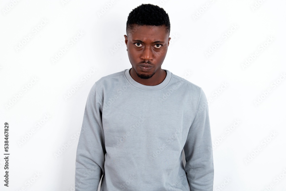 Fototapeta premium Offended dissatisfied young handsome man wearing grey sweater over white background with moody displeased expression at camera being disappointed by something