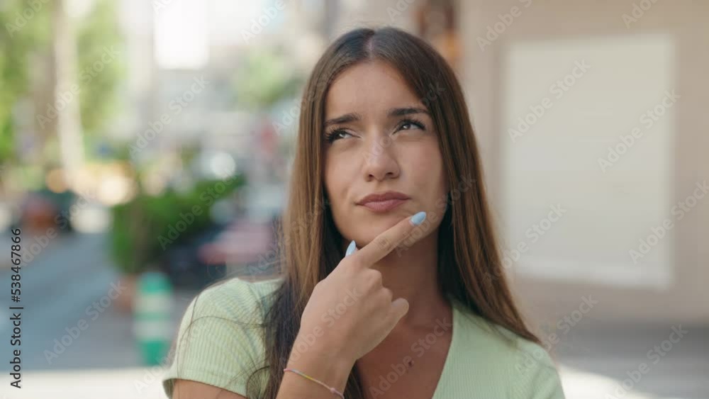 Young beautiful hispanic woman standing with doubt expression at street