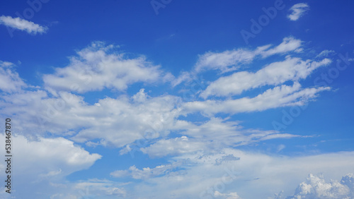 Puffy cumulus clouds under a sunny blue sky.