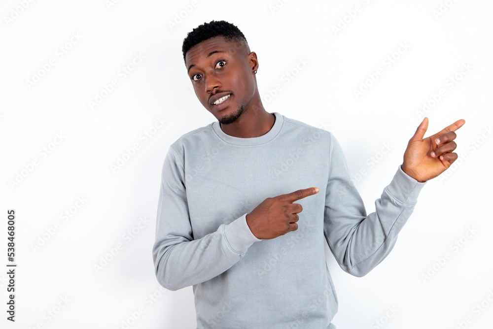 young handsome man wearing grey sweater over white background points at copy space indicates for advertising gives right direction