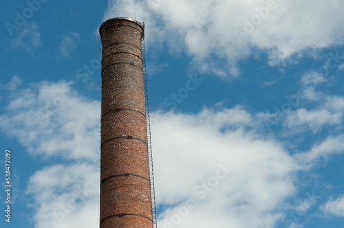 chimney or smoke stack made of brick on a cloudy blue sky