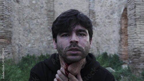 Young man falls to the ground with his throat slit. blood falling from neck. photo