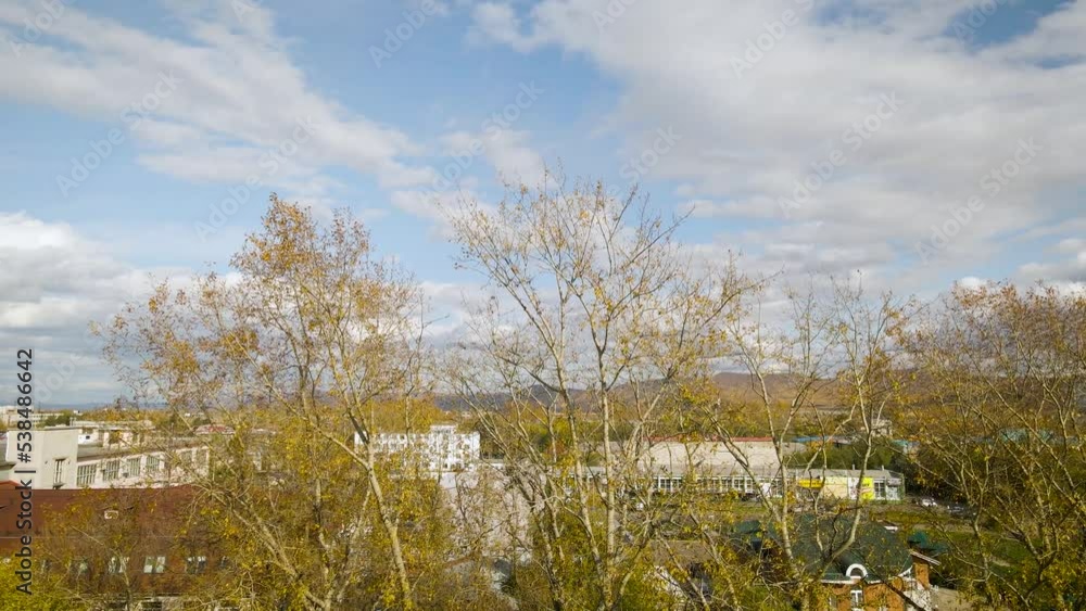 Aerial around between view of the city ferris wheel with bucket seat in golden autumn amusement park under light blue cloudy sky, drone flying inside Aerial around between view of the city ferris wheel with bucket seat in golden autumn amusement park under light blue cloudy sky, drone flying inside