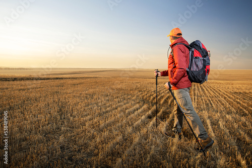  man hiker walking with backpack on field at sunset. trekking outdoor healthy lifestyle eco tourism © Sergey