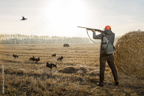 Hunter man in camouflage with a gun during the hunt on wild birds.  Autumn hunting season. photo