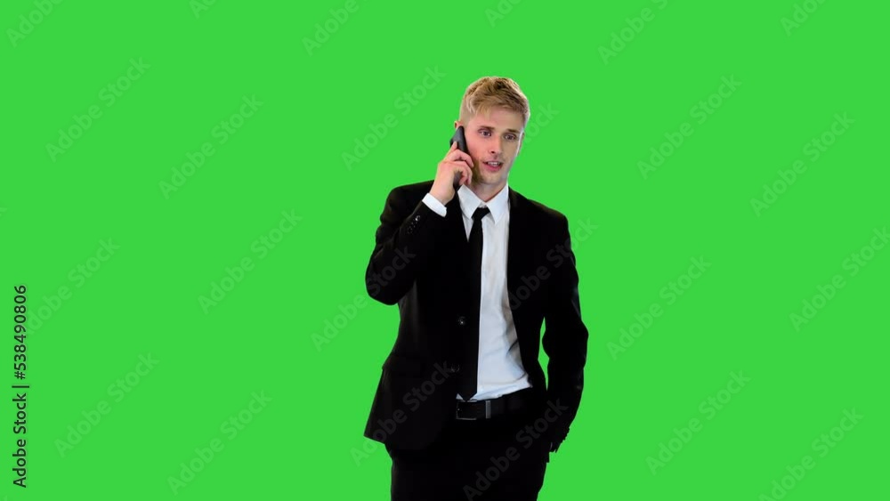 Very pleased young businessman walks talking on phone on a Green Screen, Chroma Key. Very pleased young businessman walks talking on phone on a Green Screen, Chroma Key.