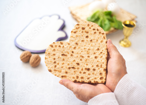 Woman's hands holds Matzah shape of heart. Traditional of Jewish Holiday on Passover. Home symbol of lovely family. top view, layout. love and care. Gift for lovers. Feeling in love and blissful life
