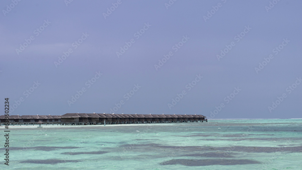 A picture of some water villas in shallow blue seas of Maldives 