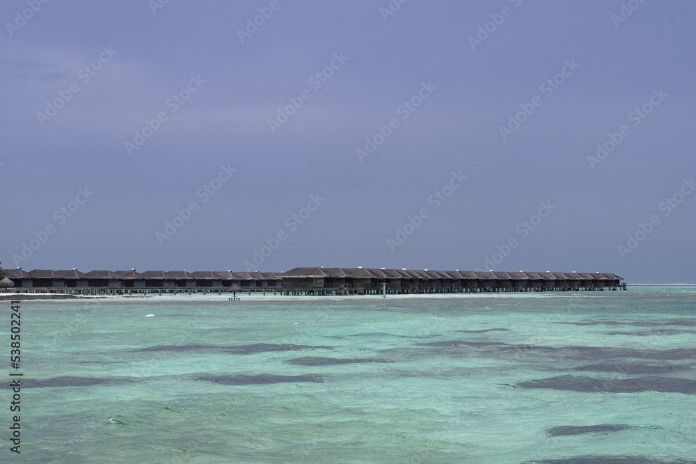 A picture of some water villas in shallow blue seas of Maldives 