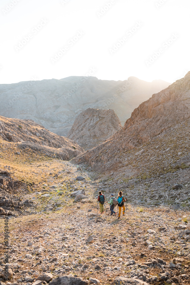 three tourists with backpacks in the mountains. Tourists travel through the rocky mountains. Active rest in mountain hiking. Adventure in the mountains.