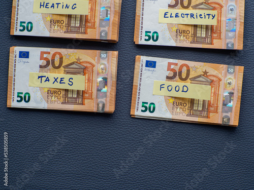 Four stack of money with inscription on the sheets for savings, cash money, euro banknotes on dark background. Home budget planning for Heating, electricity, taxes and food. Savings for life and food