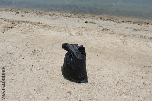 A black big trash bag on the beach © Yessi