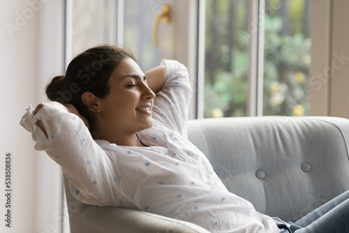 Cuadro en lienzo Serene Indian woman enjoy relaxation leaned on cozy armchair breathing fresh air inside conditioned living room