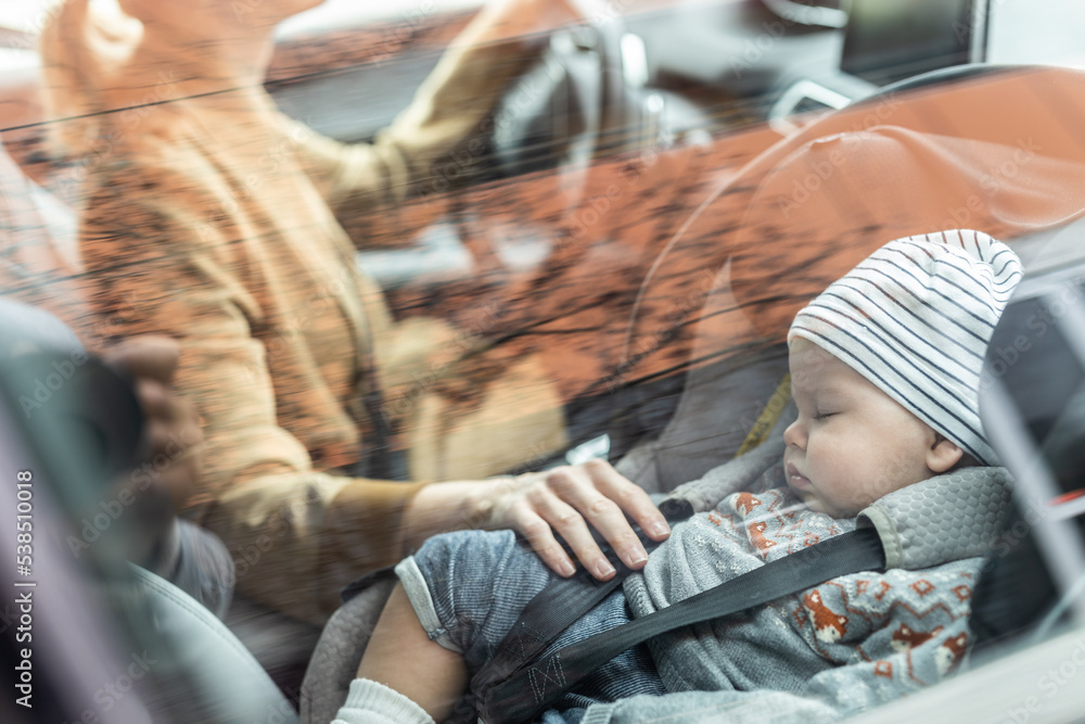 Mother concentrating on driving family car running errands while her baby sleeps in infant car seat by her site. Mother concentrating on driving family car running errands while her baby sleeps in infant car seat by her site.